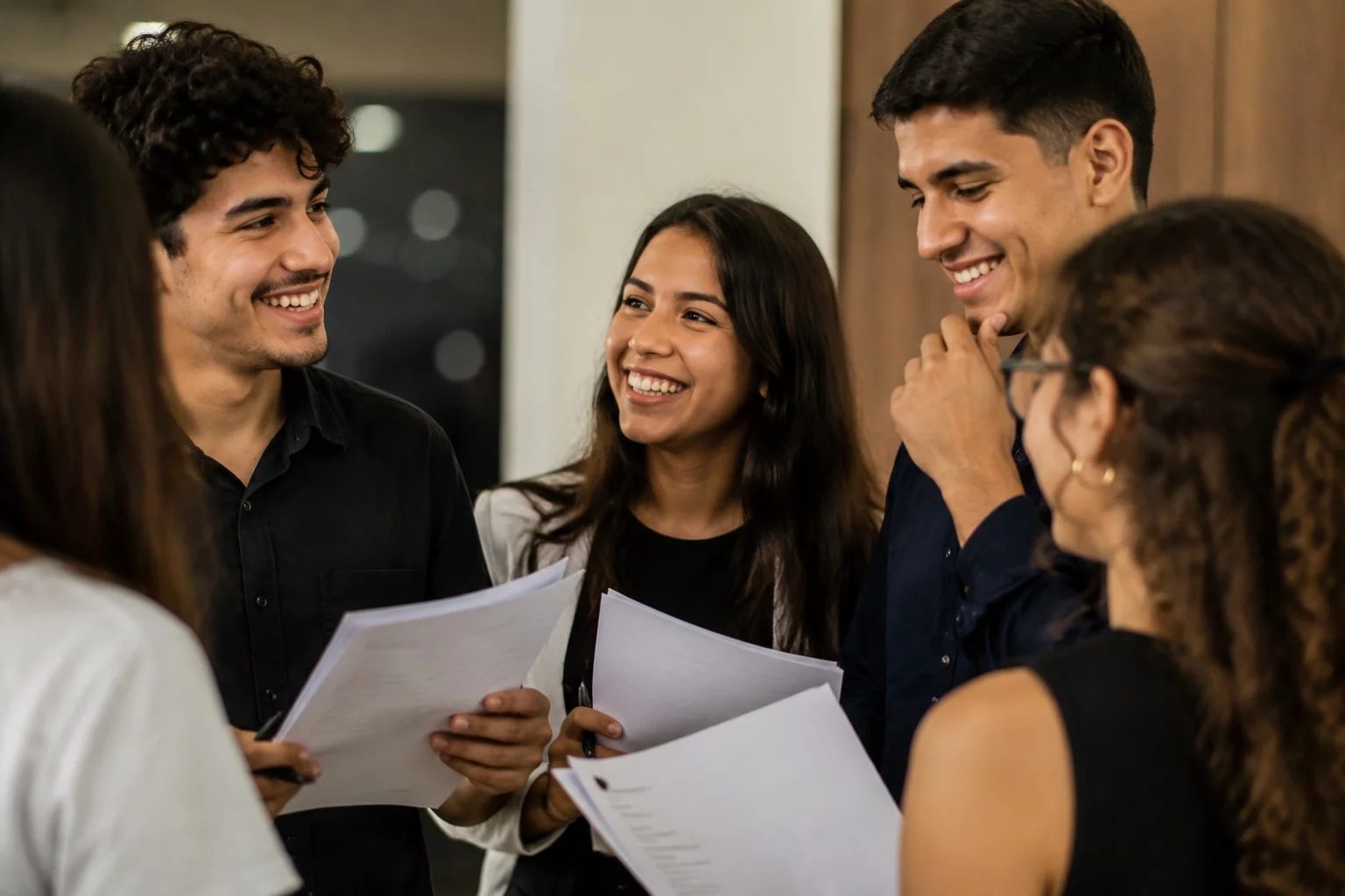 Grupo sorrindo após uma rodada de debate, com papéis nas mãos